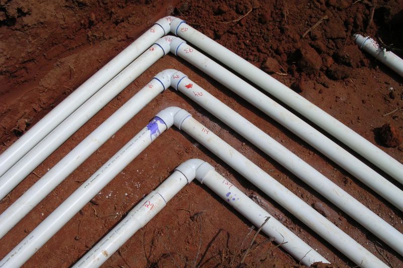 PVC pipe bends laid out on red clay before connection